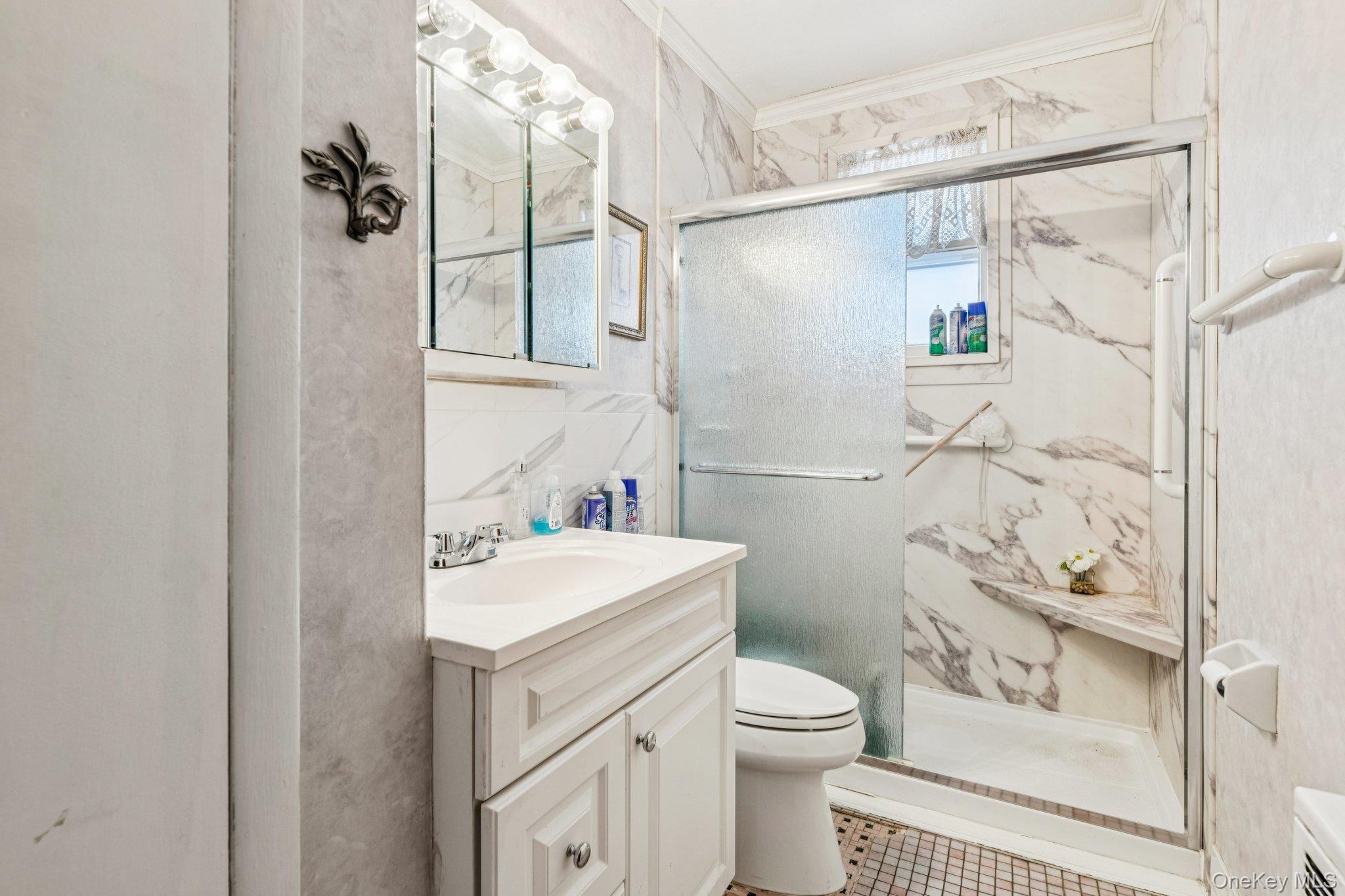 189 Surrey Commons Lynbrook, NY 11563 - Photo 11 of 14 Full bath featuring vanity, a marble finish shower, tile walls, and crown molding