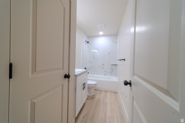 130 Pole Line Road, Unit 2 Roosevelt, UT 84066 - Photo 24 of 33 Modern bathroom featuring a white vanity with integrated sink, light wood-finish flooring, and a white bathtub with a marble-look tile surround