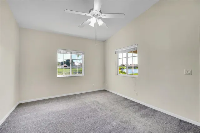 an empty room with windows and fan