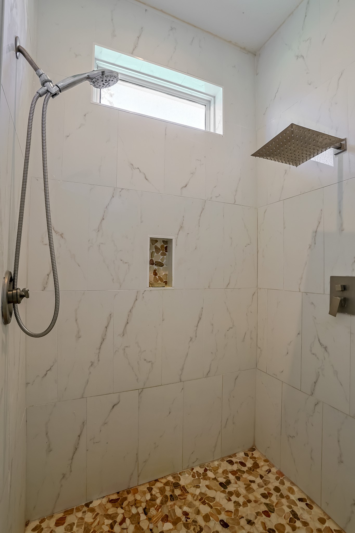 30119 West Geneva Drive Spring, TX 77386 - Photo 17 of 35 Spa-inspired walk-in shower with rainfall and handheld fixtures, accented by marble-style tile and a pebbled floor finish