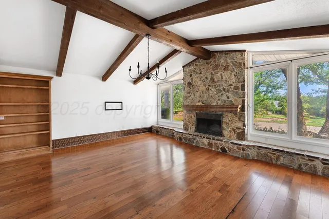 a view of empty room with wooden floor and fireplace