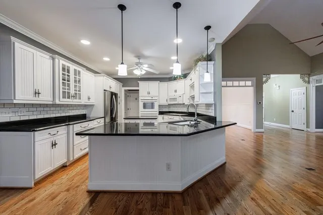 a kitchen with stainless steel appliances granite countertop a sink a stove and a wooden floor
