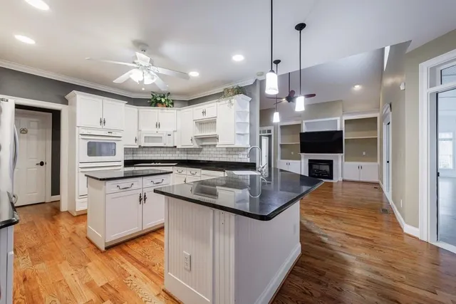 a kitchen with stainless steel appliances granite countertop a sink a stove and a wooden floors