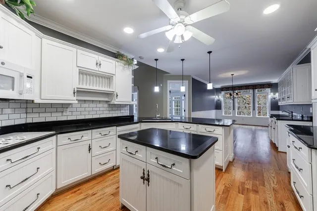 a kitchen with granite countertop a sink stainless steel appliances and white cabinets