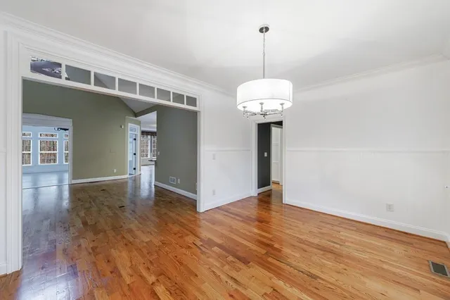 a view of a hallway with wooden floor and a chandelier