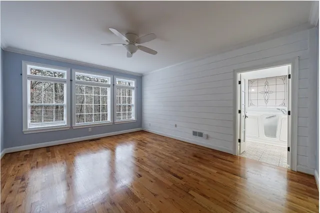 a view of empty room with wooden floor and fan