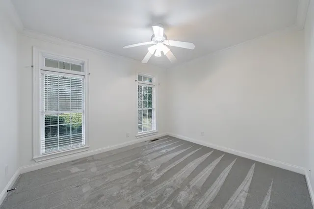 en empty room with windows and chandelier fan