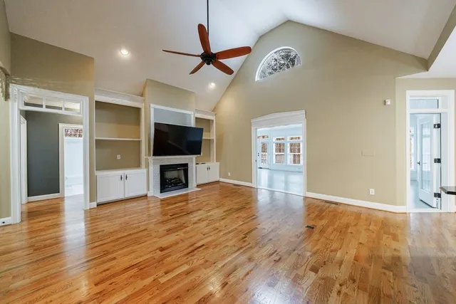 a view of a livingroom with a flat screen tv wooden floor and a ceiling fan