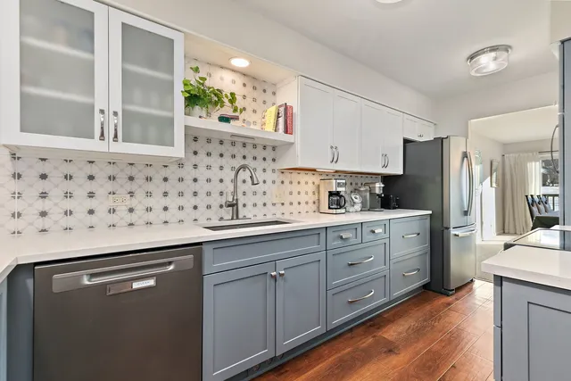 a kitchen with stainless steel appliances a sink dishwasher refrigerator and cabinets