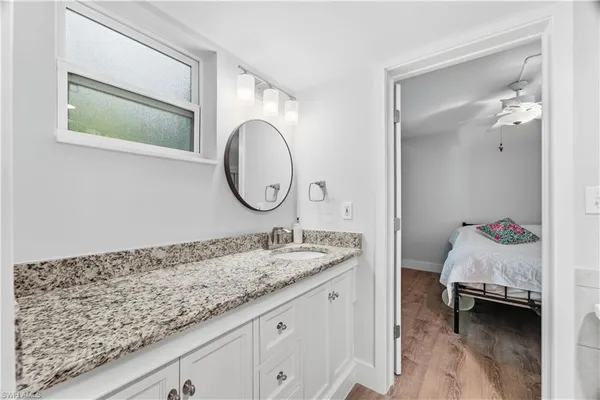a en suite bathroom with a granite countertop sink and a mirror