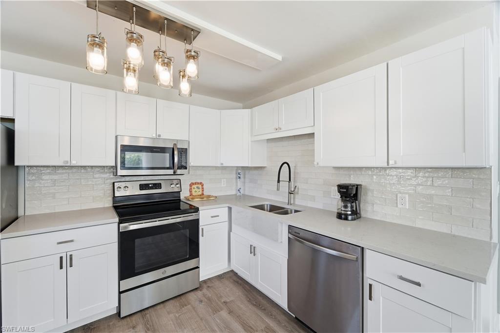 975 9th Avenue South, Unit 11 Naples, FL 34102 - Photo 2 of 19 a kitchen with cabinets stainless steel appliances a sink and wooden floor
