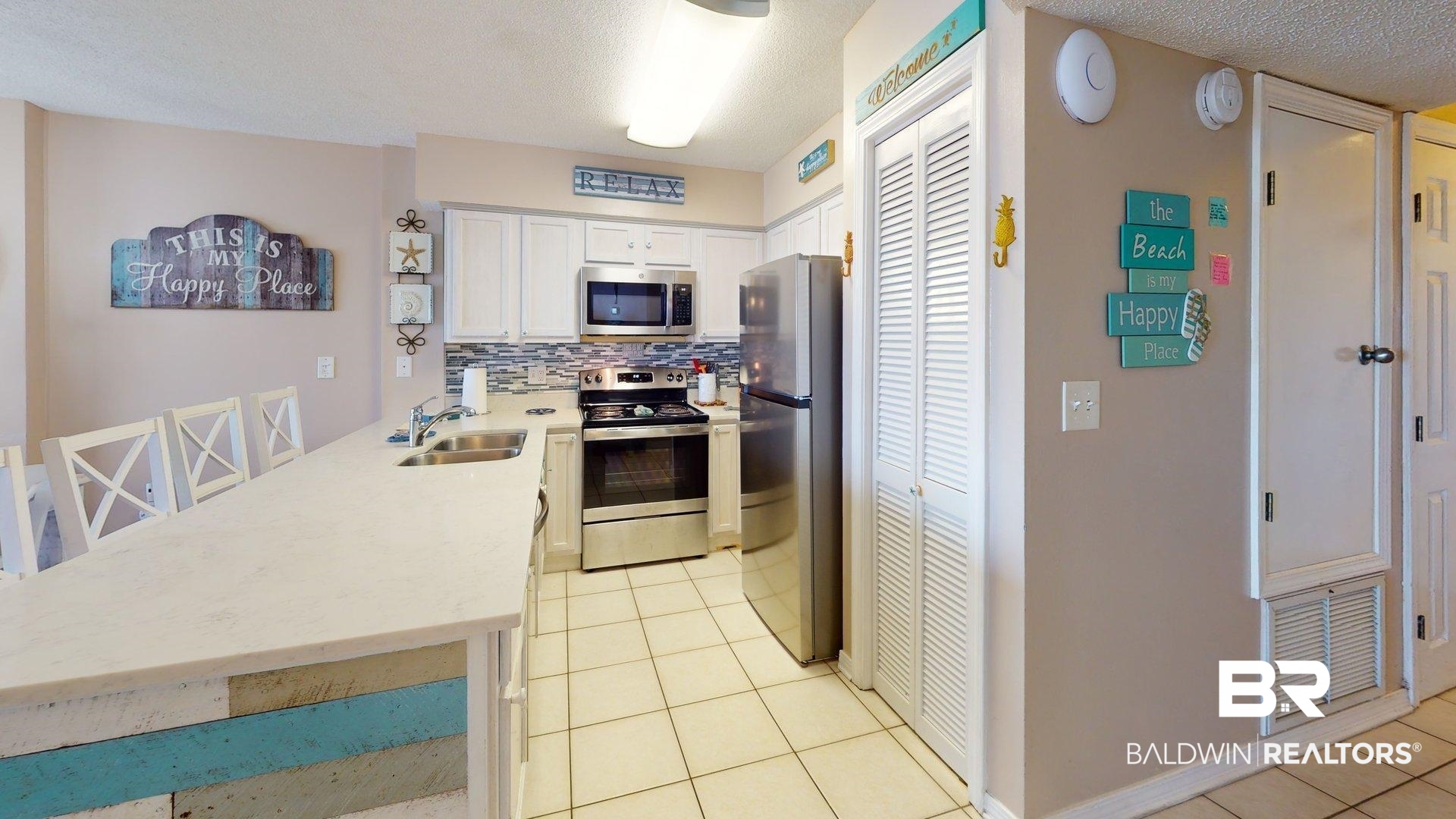 645 Plantation Road, Unit 6503 Gulf Shores, AL 36542 - Photo 10 of 53 Kitchen featuring white cabinetry, light tile patterned floors, a textured ceiling, appliances with stainless steel finishes, and a peninsula