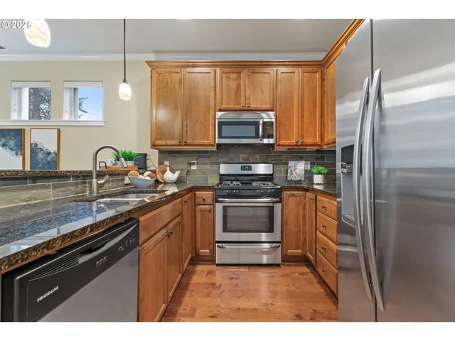 a kitchen with stainless steel appliances a stove a sink a refrigerator a window and cabinets