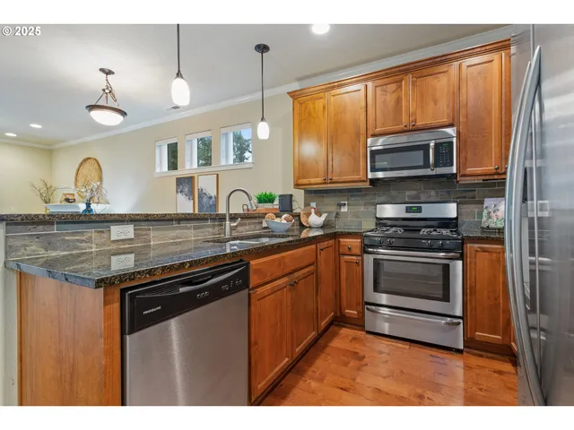 a kitchen with stainless steel appliances granite countertop a stove a sink and a microwave