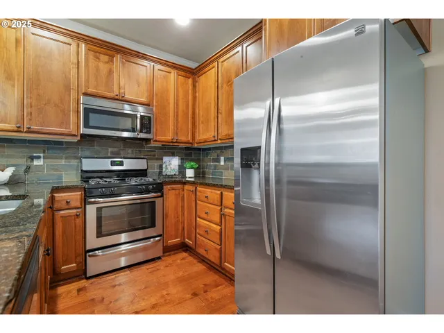 a kitchen with stainless steel appliances granite countertop a refrigerator and a stove top oven