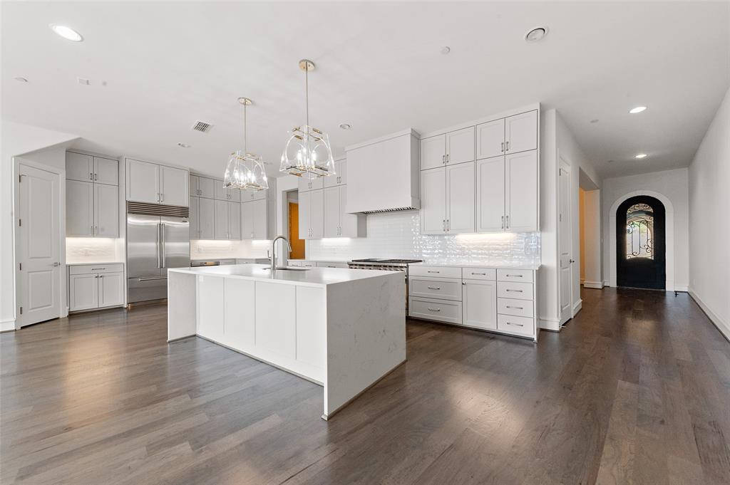 a large kitchen with kitchen island a white counter space a sink stainless steel appliances and cabinets