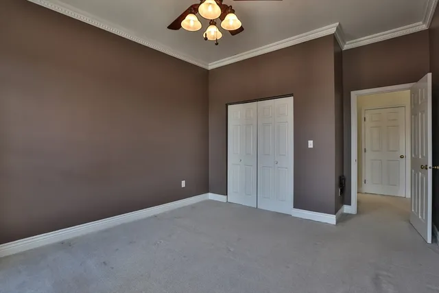 a view of an empty room with a chandelier fan