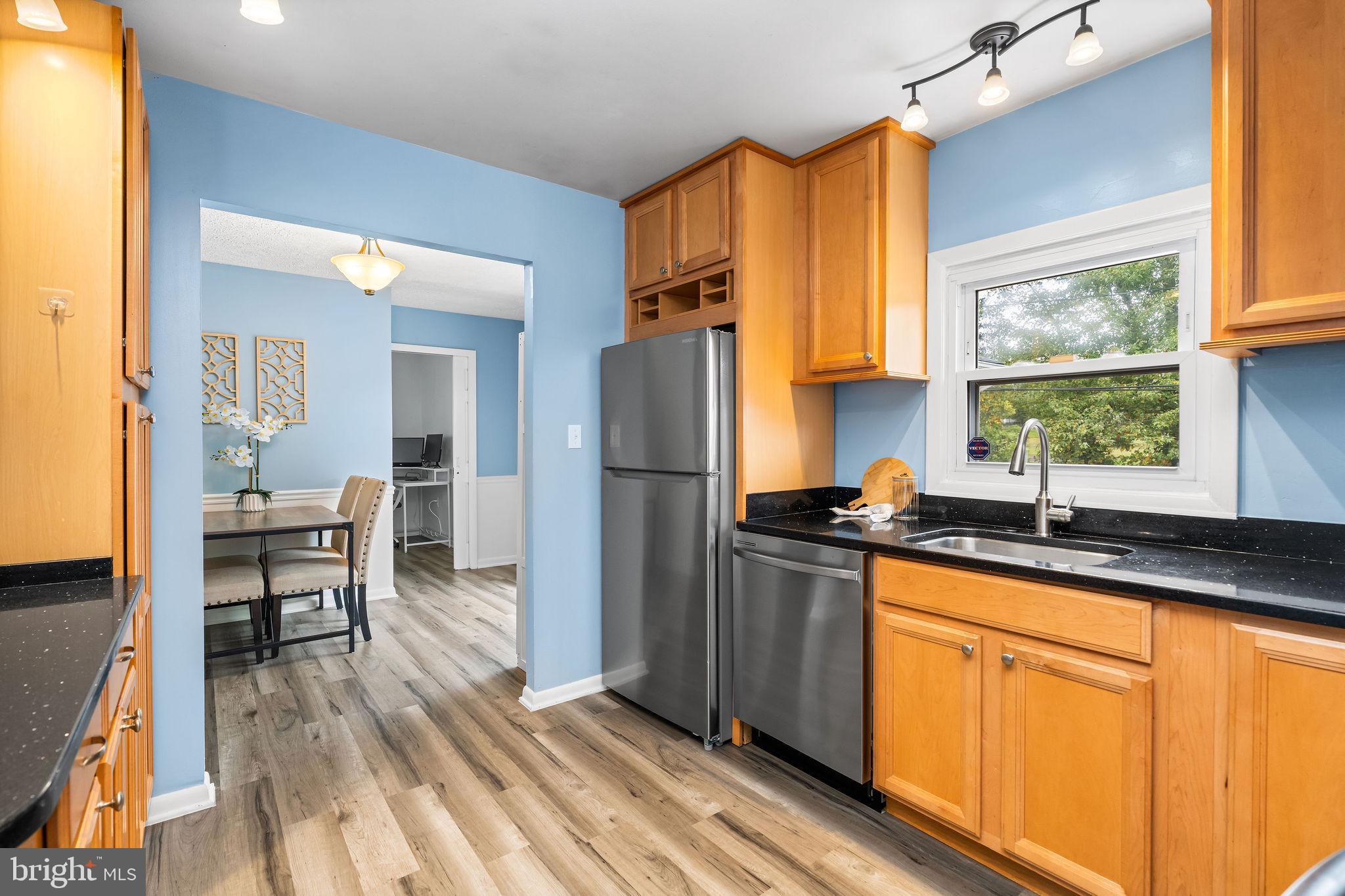 313 Park Hall South Laurel, MD 20724 - Photo 11 of 30 a kitchen with granite countertop a refrigerator stove top oven dining table and chairs