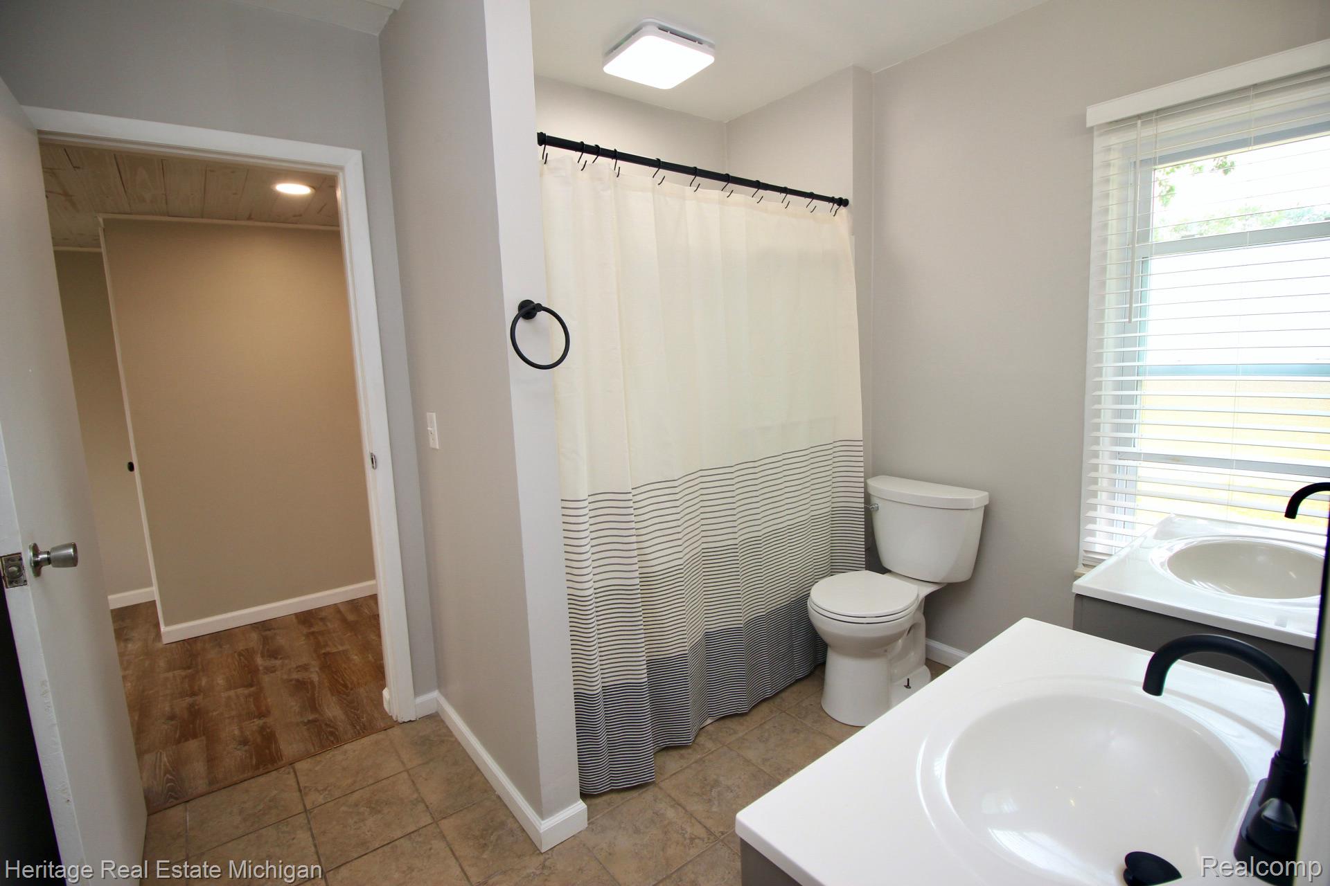 15352 South Duffield Road Byron, MI 48418 - Photo 13 of 47 Bathroom featuring dual vanities with white countertops, matte black faucets, and a shower/tub combination with a dark shower rod