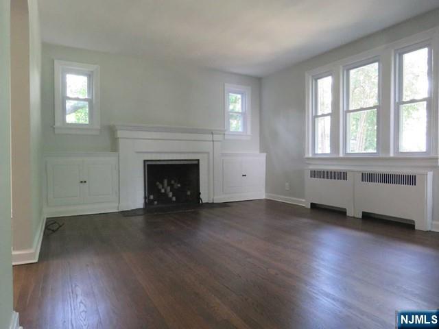 289 Hardenburgh Avenue Demarest, NJ 07627 - Photo 6 of 43 an empty room with wooden floor fireplace and windows