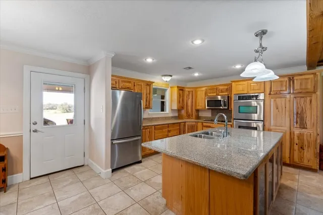 a kitchen with stainless steel appliances granite countertop a refrigerator a oven and a sink with granite countertops