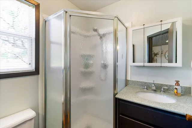 a bathroom with a granite countertop sink shower mirror and toilet