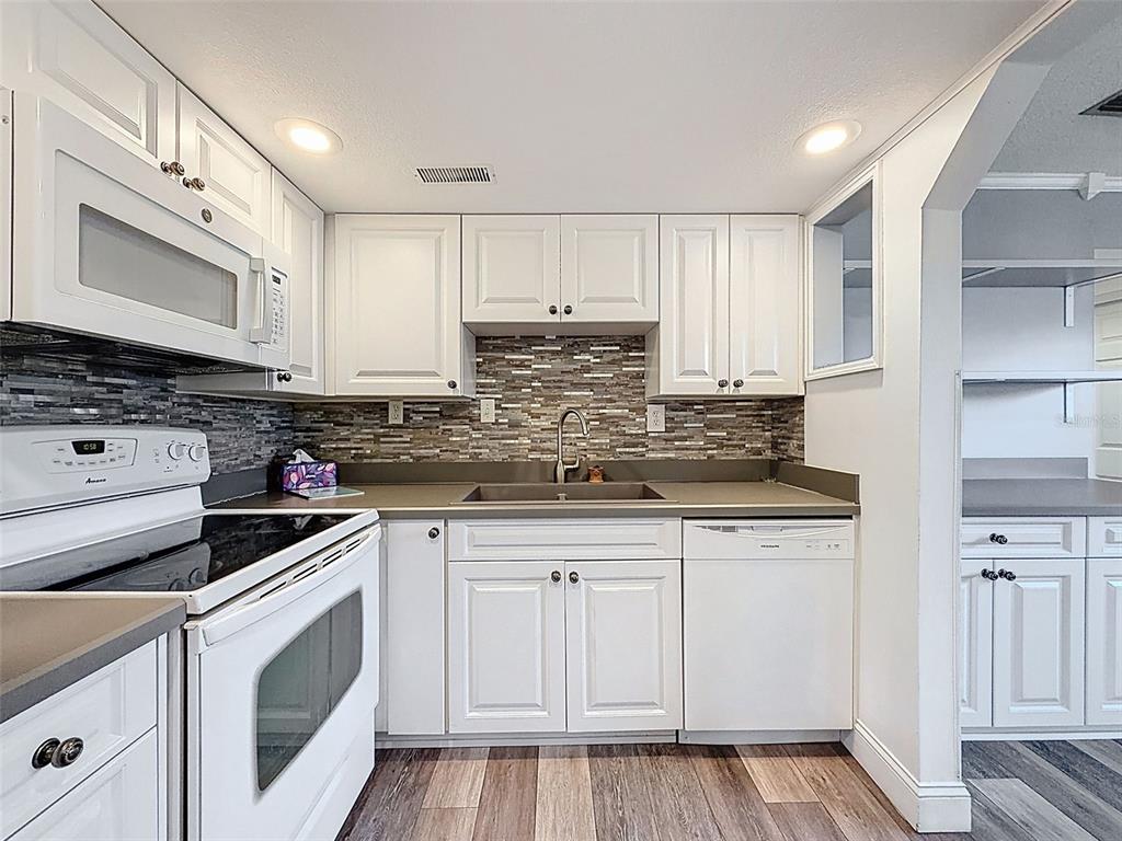 11832 Boynton Lane, Unit 24B New Port Richey, FL 34654 - Photo 11 of 42 a kitchen with granite countertop white cabinets and white appliances