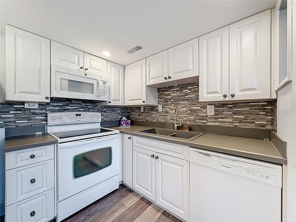 11832 Boynton Lane, Unit 24B New Port Richey, FL 34654 - Photo 12 of 42 a kitchen with white cabinets white stainless steel appliances and sink