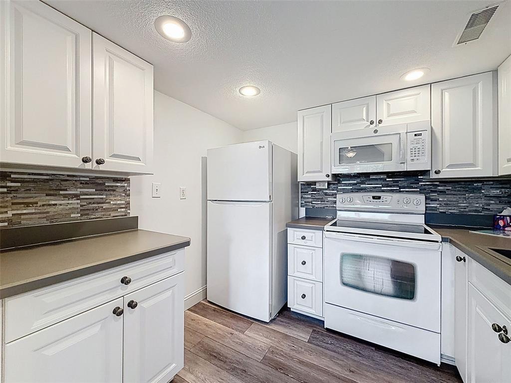 11832 Boynton Lane, Unit 24B New Port Richey, FL 34654 - Photo 14 of 42 a kitchen with white cabinets and white appliances