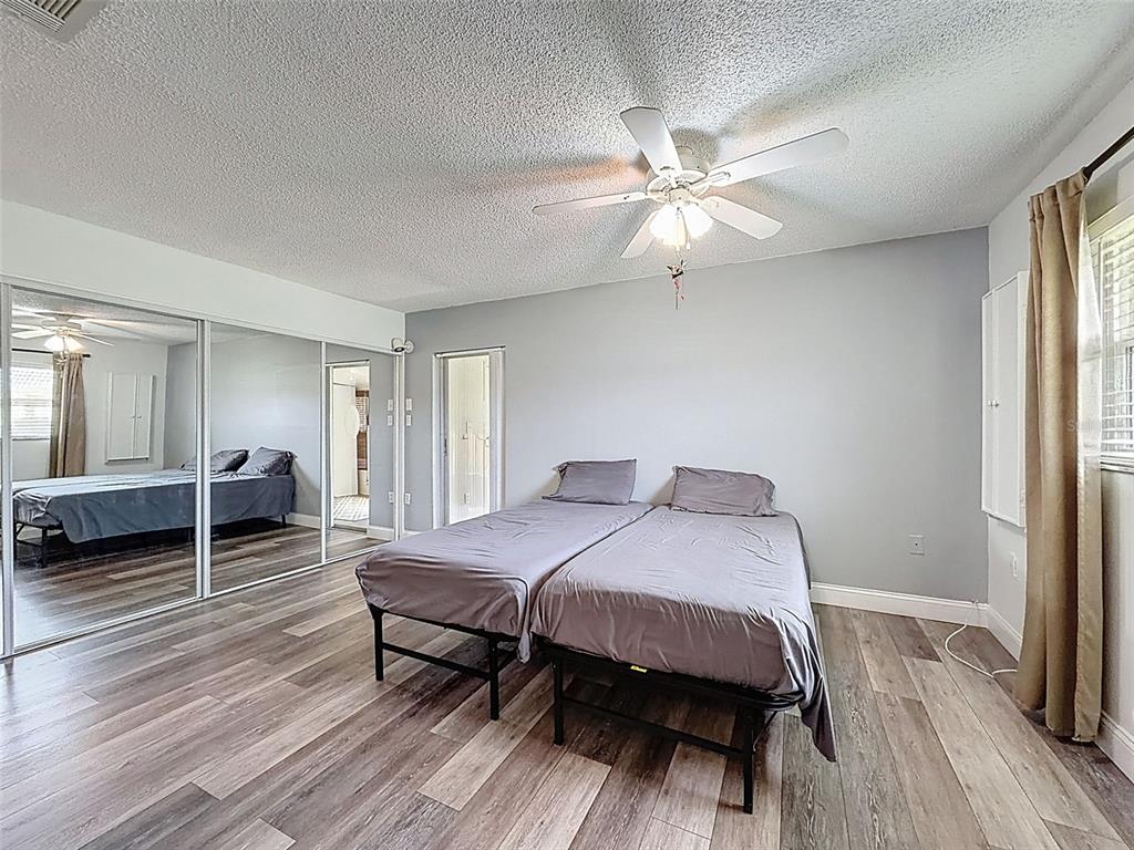11832 Boynton Lane, Unit 24B New Port Richey, FL 34654 - Photo 20 of 42 a bedroom with a bed and a chandelier