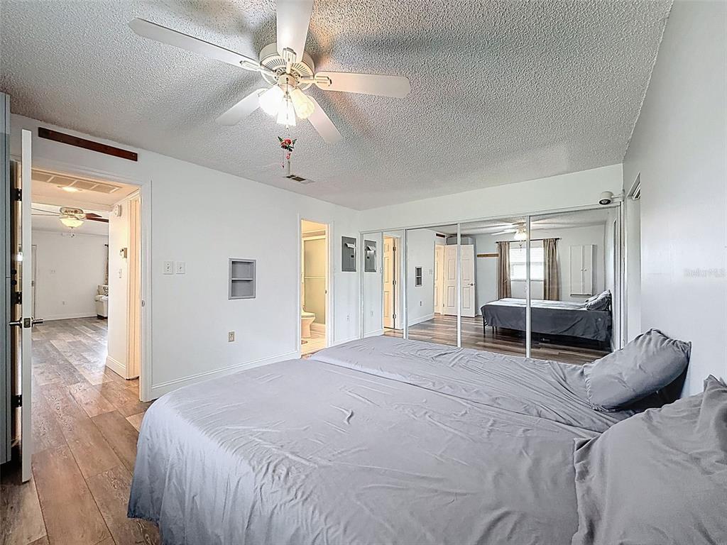 11832 Boynton Lane, Unit 24B New Port Richey, FL 34654 - Photo 22 of 42 a spacious bedroom with a bed and a chandelier