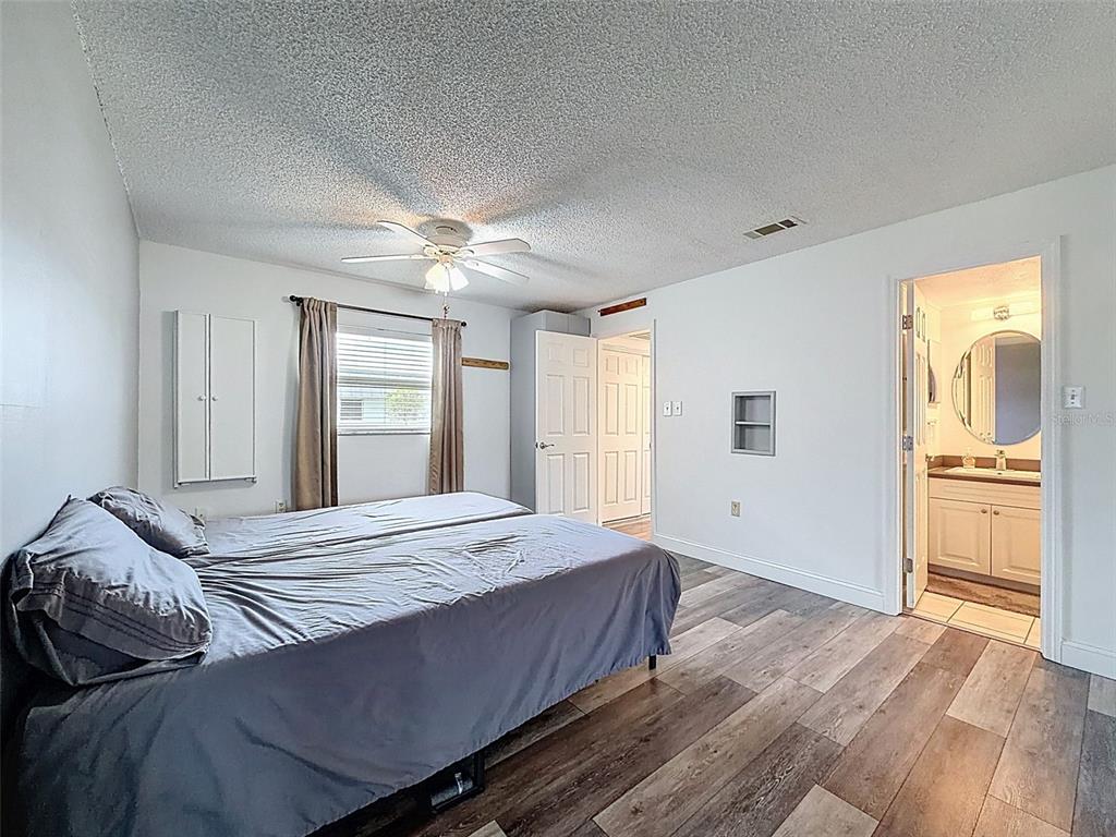 11832 Boynton Lane, Unit 24B New Port Richey, FL 34654 - Photo 23 of 42 a bedroom with a large bed a chandelier and a window