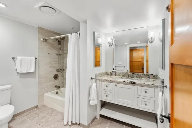 a spacious bathroom with a granite countertop sink mirror and a bathtub