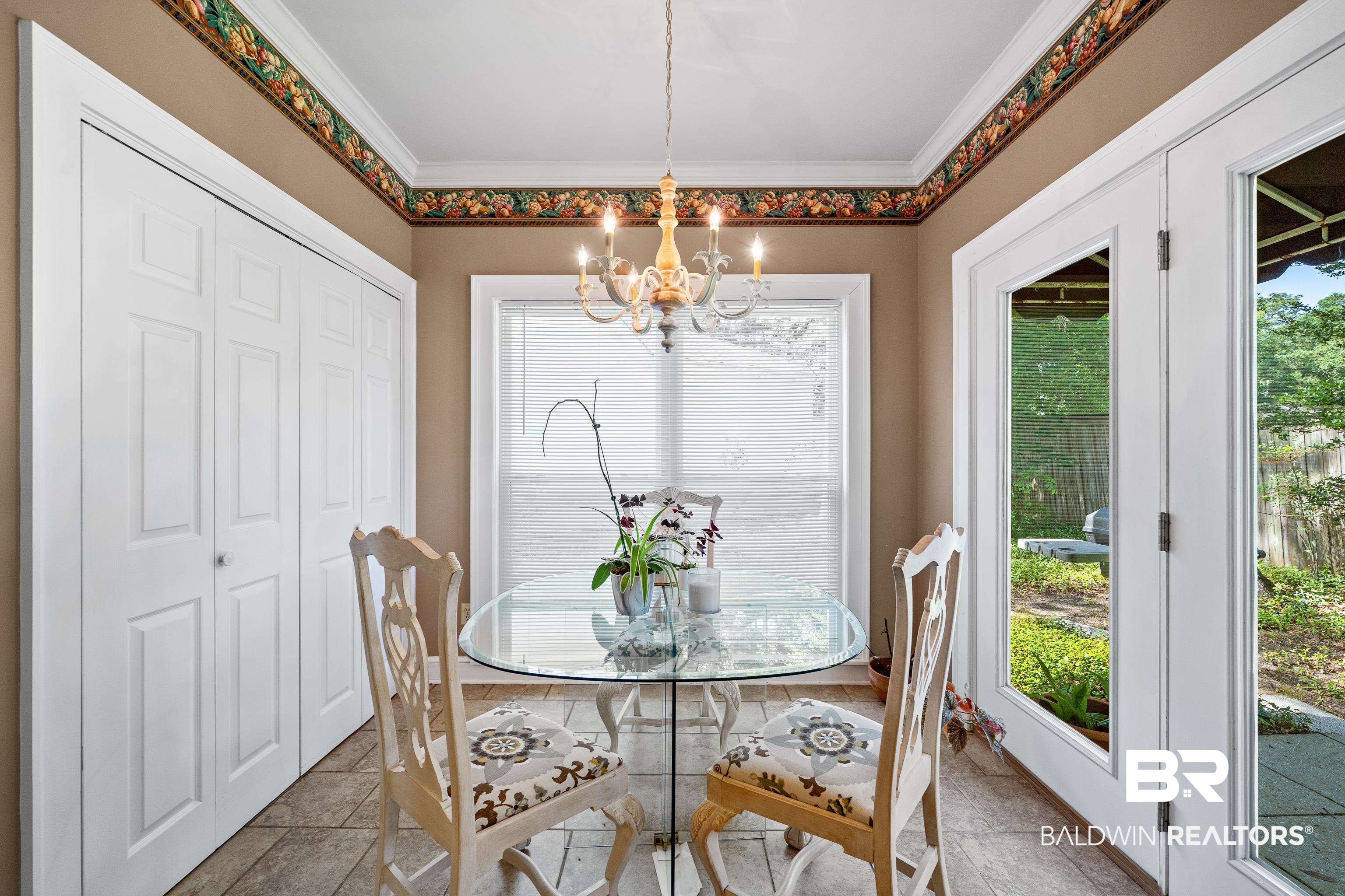 4272 Bit And Spur Road, Unit 12 Mobile, AL 36608 - Photo 15 of 34 Dining area featuring a chandelier, stone tile floors, and ornamental molding