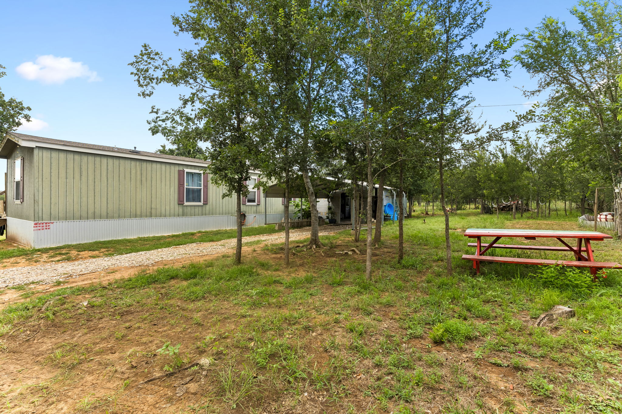 253 North County Line Road, Unit C Elgin, TX 78621 - Photo 26 of 39 A quaint residence sits amidst a natural, treed landscape with a charming picnic table.