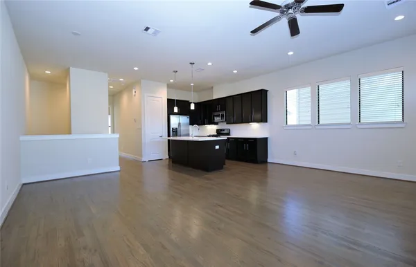 a view of kitchen and kitchen with furniture a ceiling fan and wooden floor