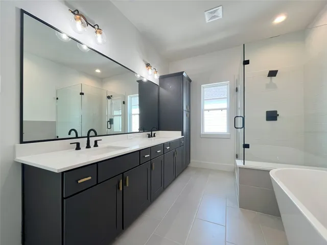 a spacious bathroom with a bathtub shower sink mirror and toilet