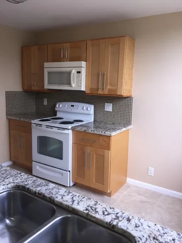 a kitchen with granite countertop a stove top oven microwave and cabinets