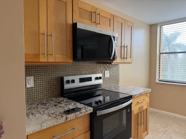 a kitchen with granite countertop a refrigerator and a stove top oven