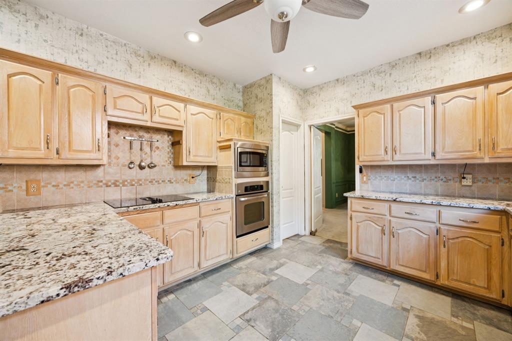 2604 Spring Lake Drive Richardson, TX 75082 - Photo 13 of 34 a kitchen with stainless steel appliances granite countertop a stove top oven a sink dishwasher and a refrigerator with wooden cabinets