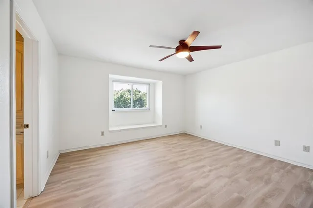 an empty room with windows fireplace and a ceiling fan