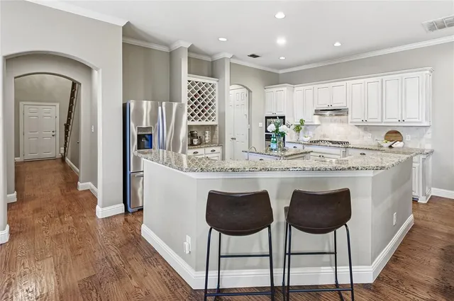 a kitchen with stainless steel appliances granite countertop a table chairs sink and cabinets