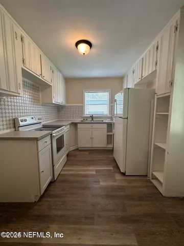 a kitchen with a sink a refrigerator and cabinets