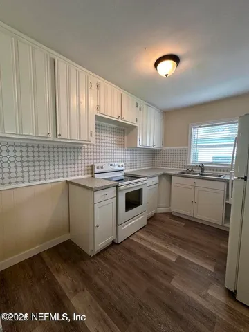 a kitchen with granite countertop white cabinets and white appliances