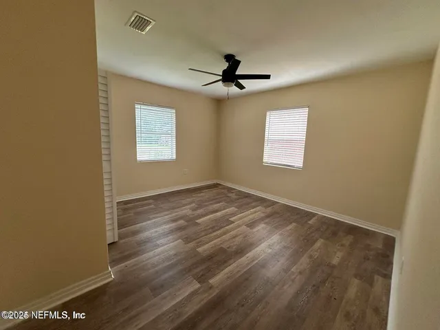 an empty room with windows and fan