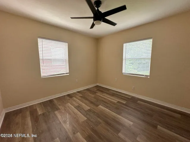 a view of an empty room with a window and wooden floor
