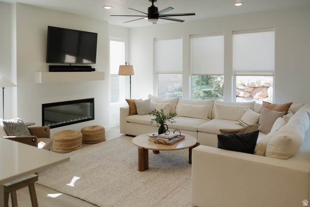 629 Spring Lily Drive St. George, UT 84790 - Photo 4 of 50 Living area featuring a modern fireplace with a floating mantel, large windows with roller blinds, a ceiling fan with integrated lighting, and light wood-finish flooring