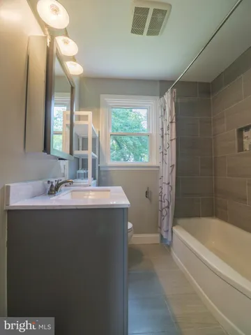 a bathroom with a granite countertop sink mirror and a bathtub