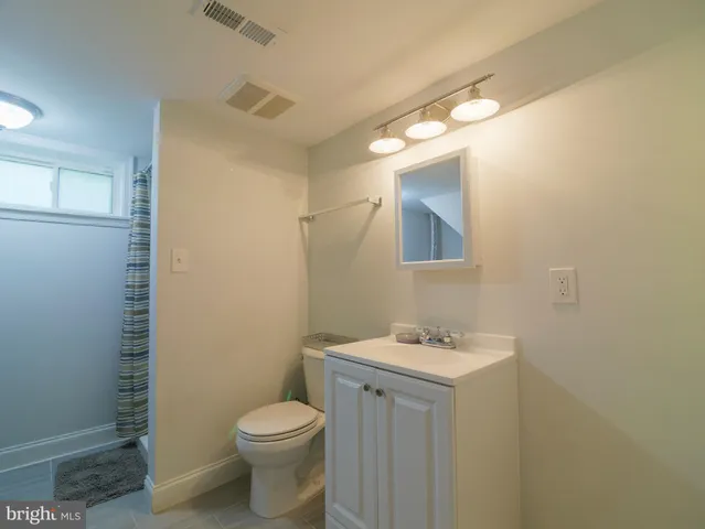 a bathroom with a toilet sink vanity and mirror