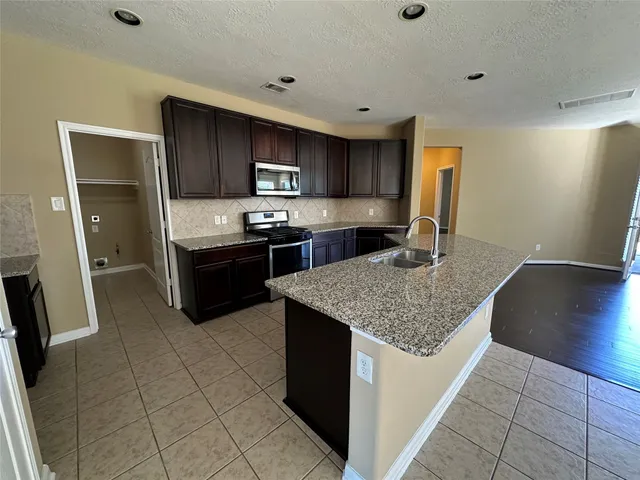 a kitchen with stainless steel appliances granite countertop a sink refrigerator and cabinets